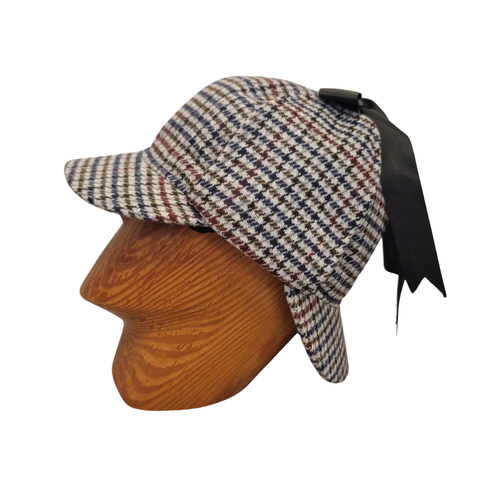 A classic deerstalker hat with a grey,  brown, black, and white houndstooth pattern, displayed on a wooden mannequin head against a plain white background. Side