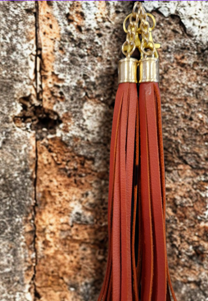 Rust coloured handmade leather boot tassel hanging on a wall